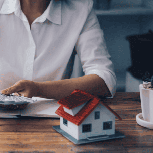 Person reviewing paperwork with a house model on the desk.