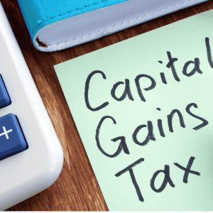 Handwritten note about capital gains tax on a green sticky note.