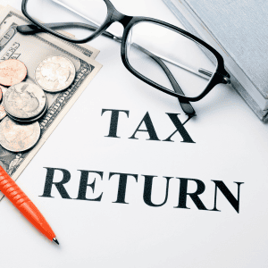 Tax return form with glasses, coins, and a pen for home sale taxes in Virginia.