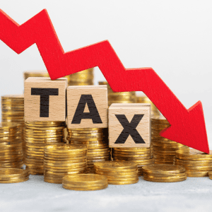 Red downward arrow over stacked coins with 'TAX' blocks for real estate tax.