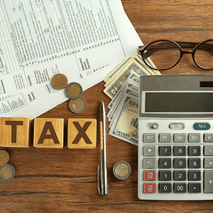Financial documents, calculator, and coins on wooden table for tax planning.