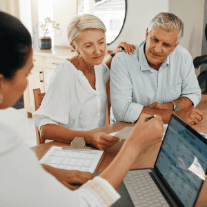 Elderly couple consulting with real estate agent about house sale.