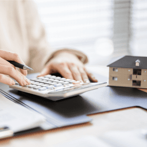 Person calculating mortgage or property investment with house model.