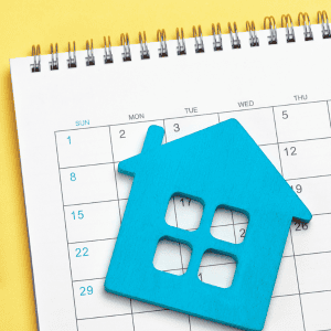 Blue house-shaped cutout on a calendar for house selling timeline.