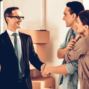 Real estate agent shaking hands with a couple in a home setting.