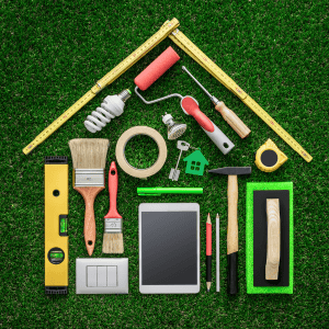 Assorted home repair tools on green grass background for renovation projects.