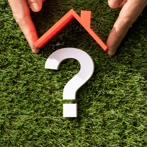 Hands holding a red arrow and a white question mark on grass.