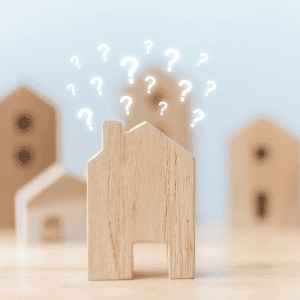 Wooden house model with question marks above, symbolizing rental property questions.