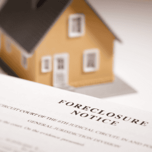 Foreclosure notice document with a small house model in the background.