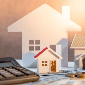Miniature house models with a large house silhouette in the background for real estate.