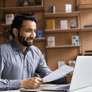 Happy man reviewing documents at home office for house selling.