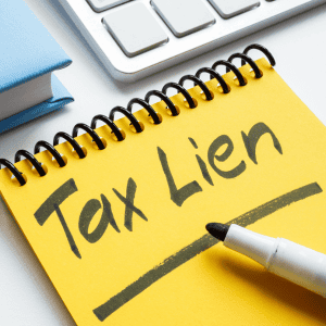 Tax lien document with pen on yellow notepad for property buyers.