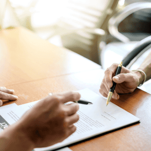 Person signing documents related to home sale and mortgage debt.