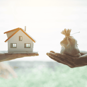 Person holding a small house model and a money bag representing mortgage debt.