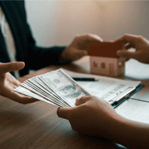 Person exchanging money for house model, real estate transaction concept.
