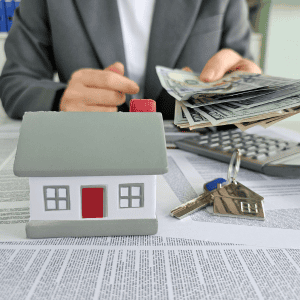 Person handling mortgage documents with house keys and calculator.